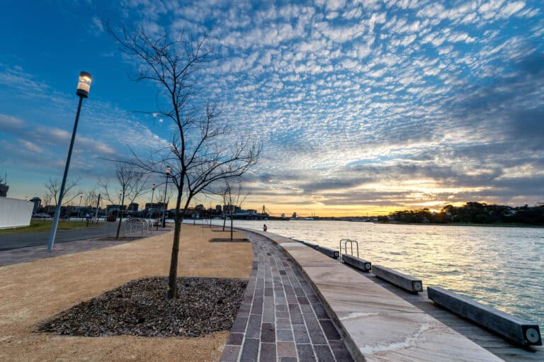 Urban riverfront park with soil, trees, and pathway during sunset for soil science and environmental studies.