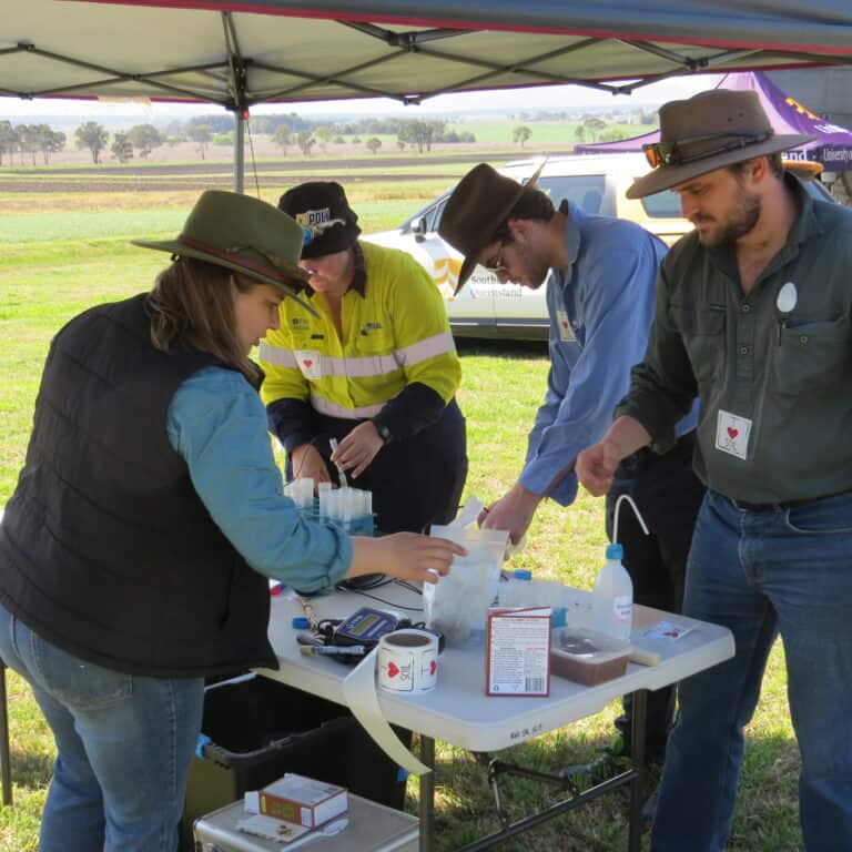 Soil science professionals conducting soil testing and analysis outdoors in a rural environment.