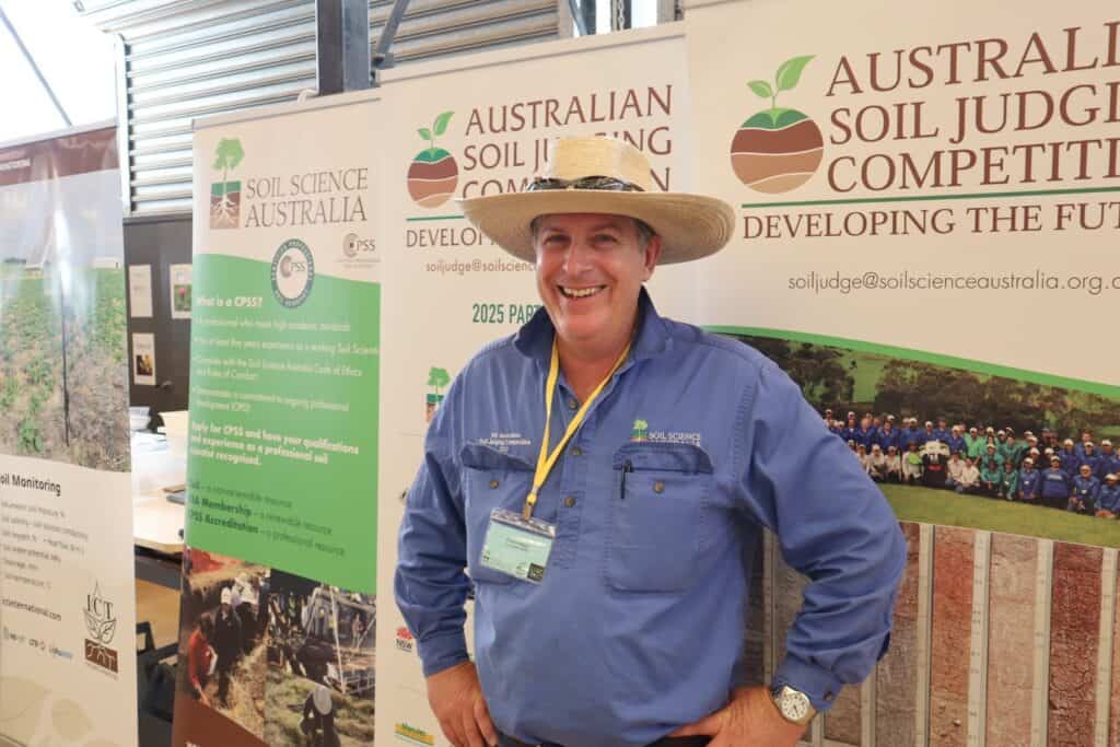 Soil science professional standing at Australian Soil Judging Competition booth, promoting sustainable soil management.