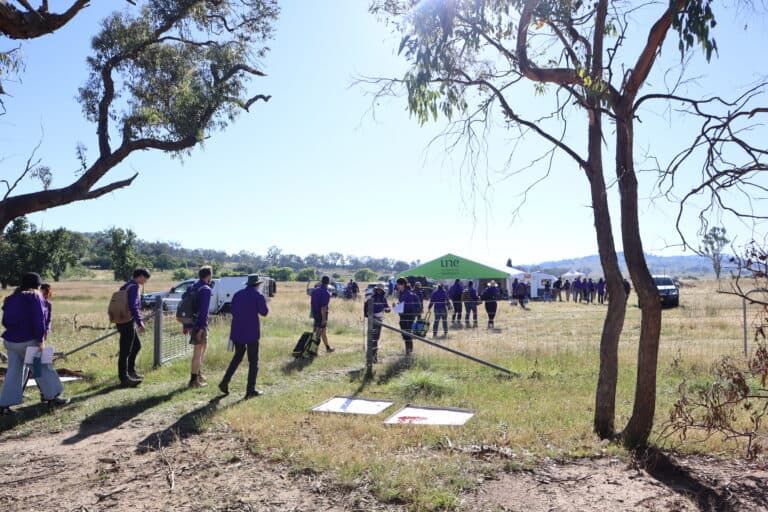 People conducting soil science field studies in a rural outdoor environment.