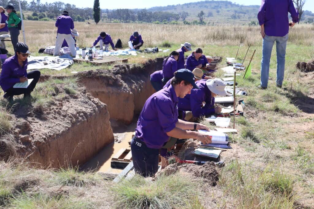 Soil scientists analyzing soil profiles in an outdoor field study, focusing on soil health and composition.